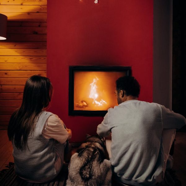 pexels-photo-6530544-6530544-2 A couple and their dog enjoying a warm evening by the fireplace indoors.